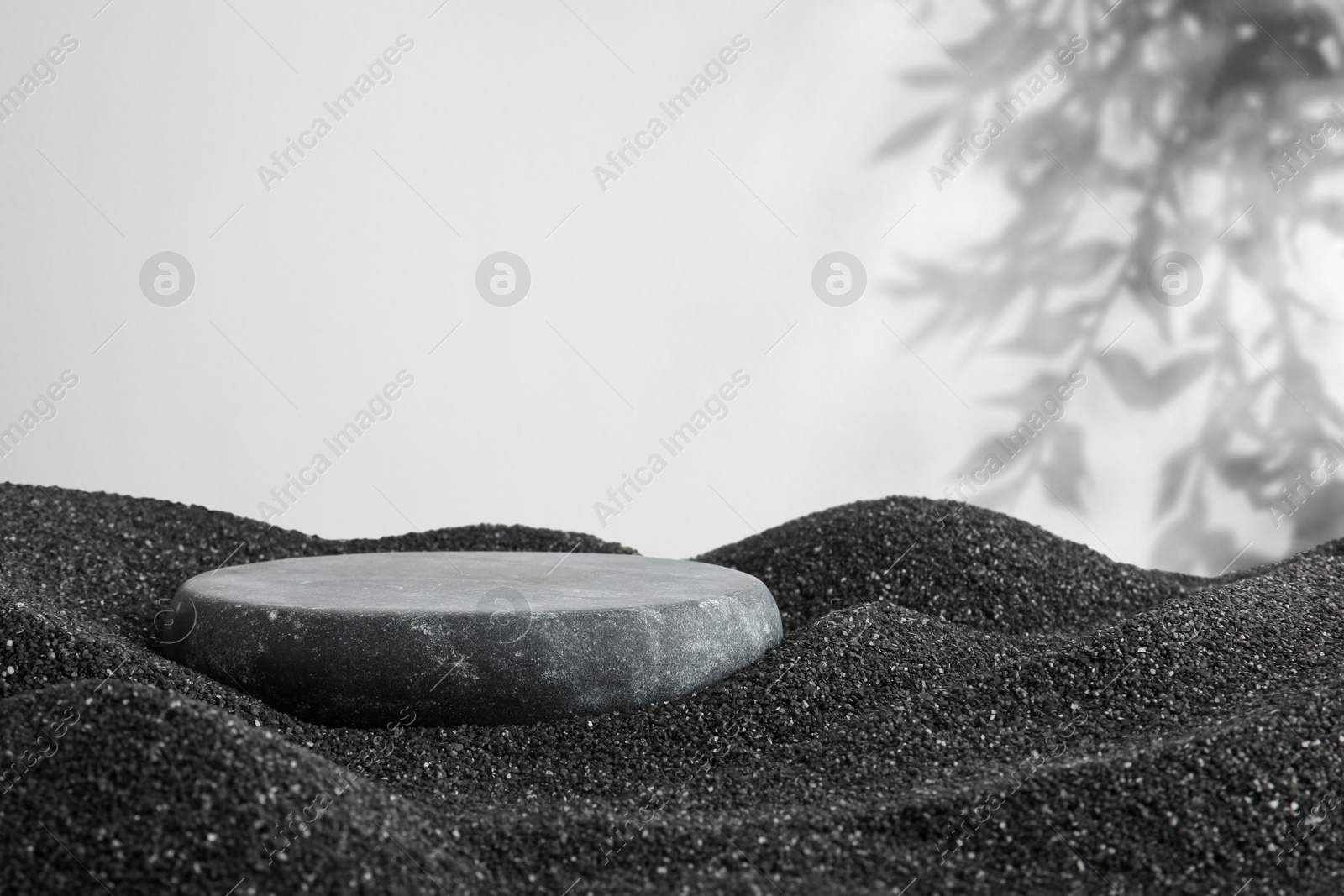 Image of Podium for product presentation. Stone on black sand against white background with shadow. Stylish promotion poster