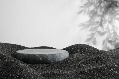 Image of Podium for product presentation. Stone on black sand against white background with shadow. Stylish promotion poster