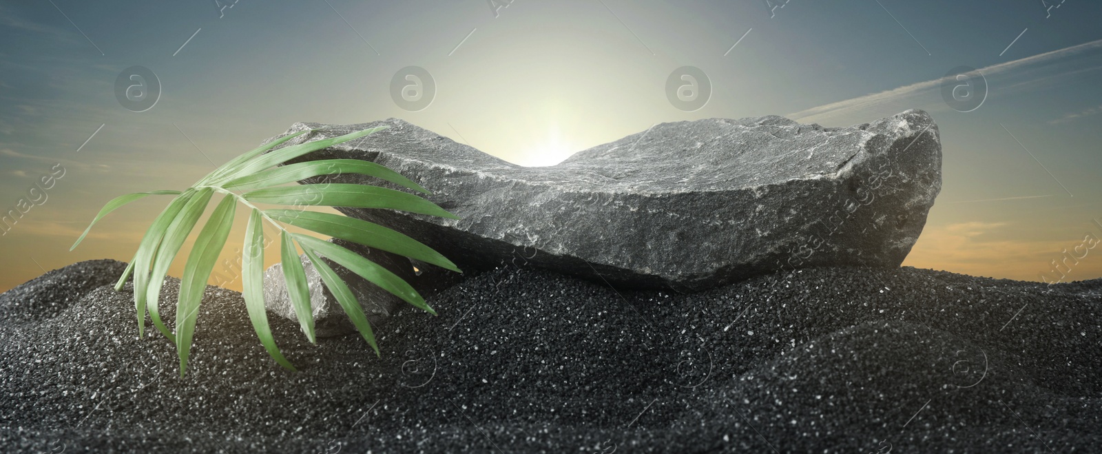 Podium for product presentation. Stone and green leaf on black sand under sky, banner design. Stylish promotion poster Image of Podium for product presentation. Stone and green leaf on black sand under sky, banner design. Stylish promotion poster