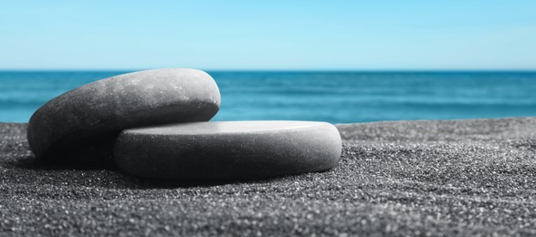 Image of Podium for product presentation. Stones on sand near sea, banner design. Stylish promotion poster
