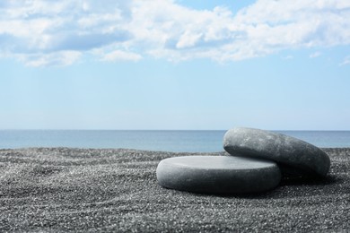 Image of Podium for product presentation. Stones on sand near sea. Stylish promotion poster