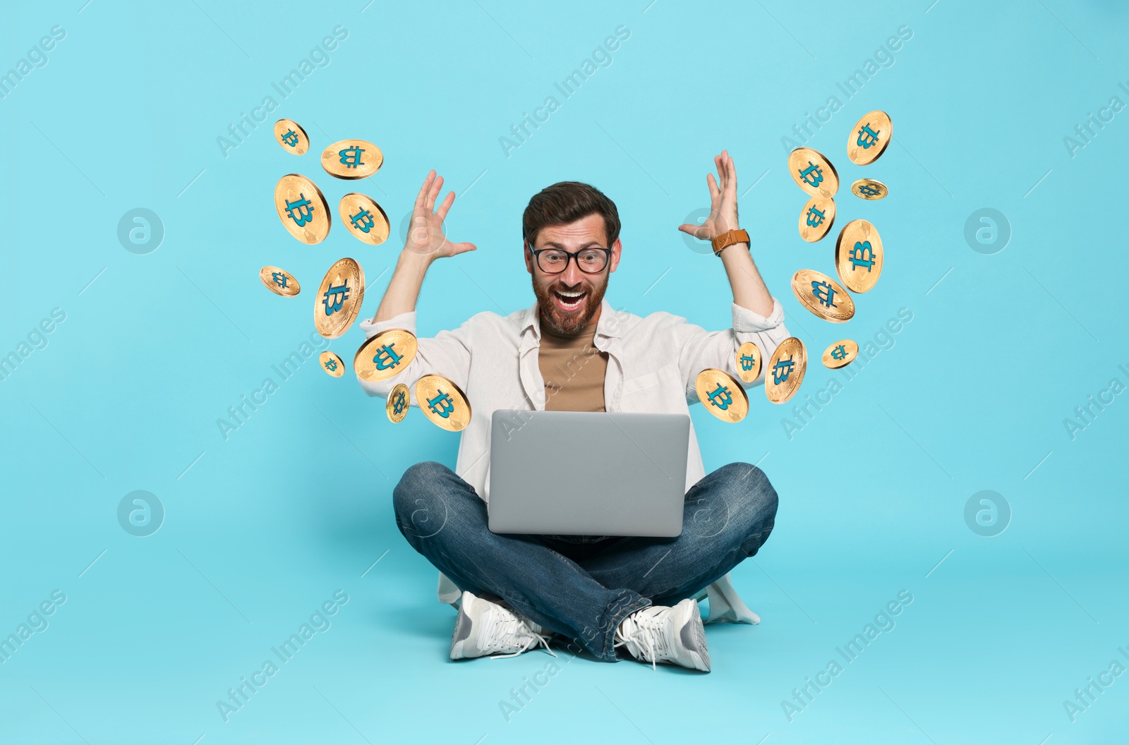 Cryptocurrency. Happy man with laptop on light blue background. Bitcoins flying out of device Image of Cryptocurrency. Happy man with laptop on light blue background. Bitcoins flying out of device