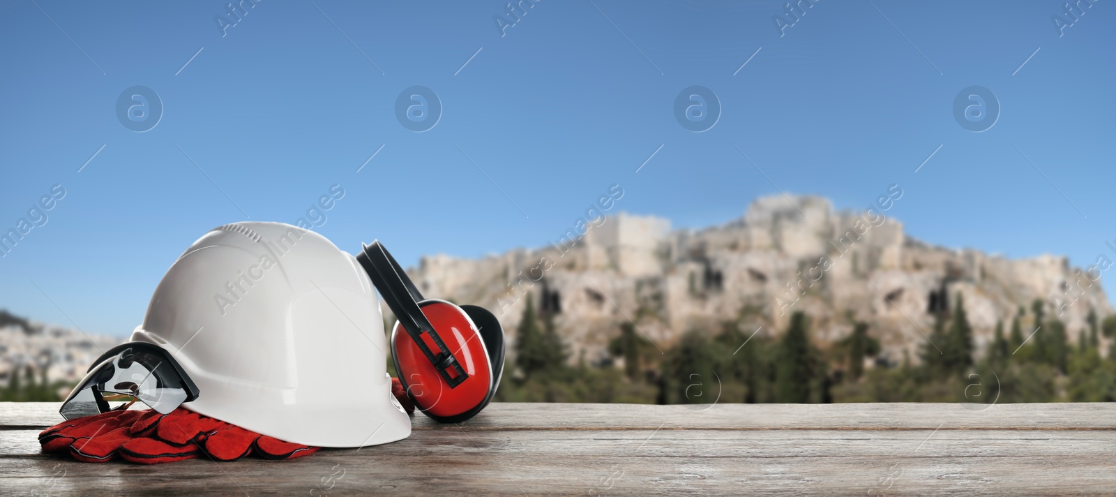 Set of safety equipment on wooden table against blurred landscape. Banner design with space for text Image of Set of safety equipment on wooden table against blurred landscape. Banner design with space for text