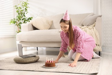 Photo of Birthday celebration. Happy woman with tasty cake having video call via laptop at home