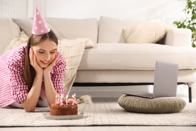 Photo of Birthday celebration. Happy woman with tasty cake having video call via laptop at home
