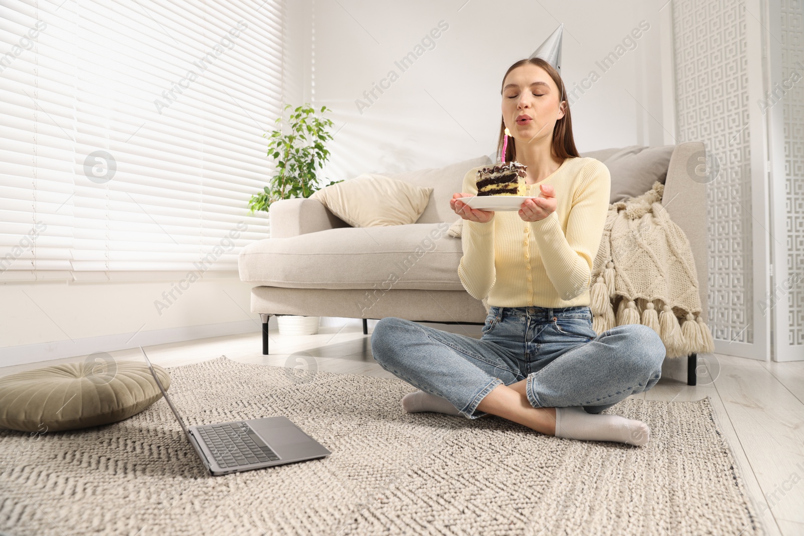 Birthday celebration. Woman blowing candle on piece of cake while having video call via laptop at home Photo of Birthday celebration. Woman blowing candle on piece of cake while having video call via laptop at home