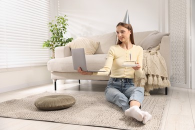 Photo of Birthday celebration. Happy woman with piece of cake having video call via laptop at home