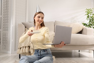 Photo of Birthday celebration. Happy woman with piece of cake having video call via laptop at home