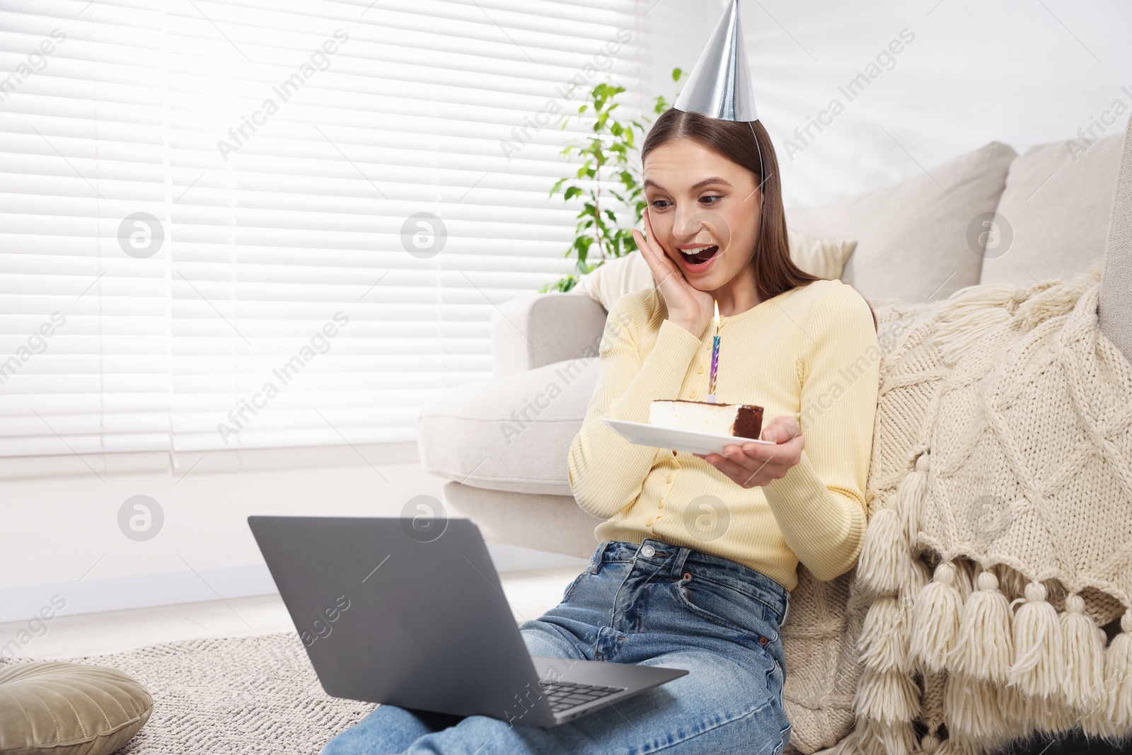 Photo of Birthday celebration. Happy woman with piece of cake having video call via laptop at home