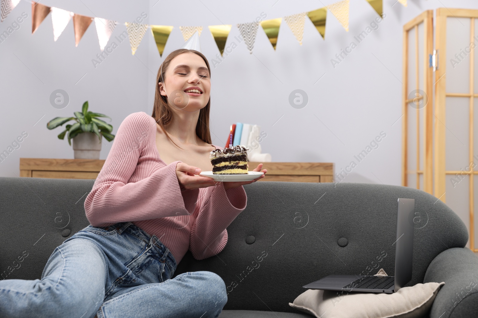 Birthday celebration. Happy woman with piece of cake having video call via laptop on sofa at home Photo of Birthday celebration. Happy woman with piece of cake having video call via laptop on sofa at home