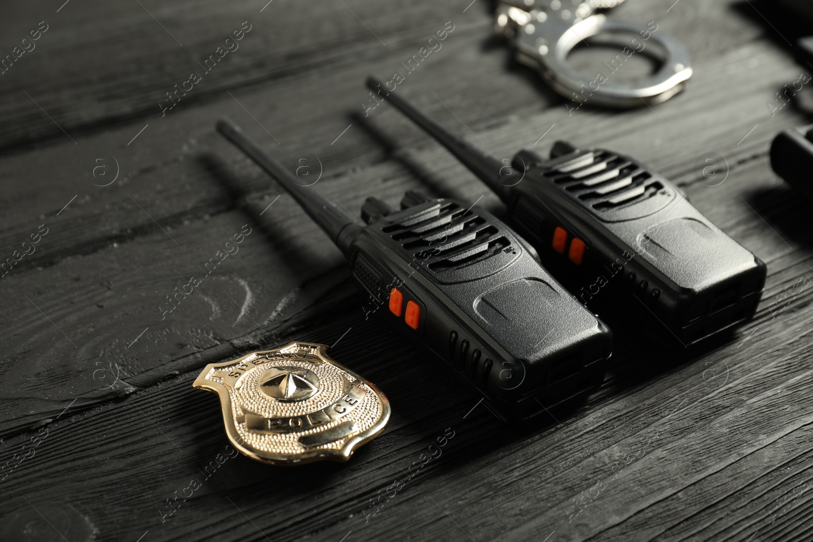 Walkie talkies, badge and handcuffs on black wooden table, closeup. Police equipment Photo of Walkie talkies, badge and handcuffs on black wooden table, closeup. Police equipment
