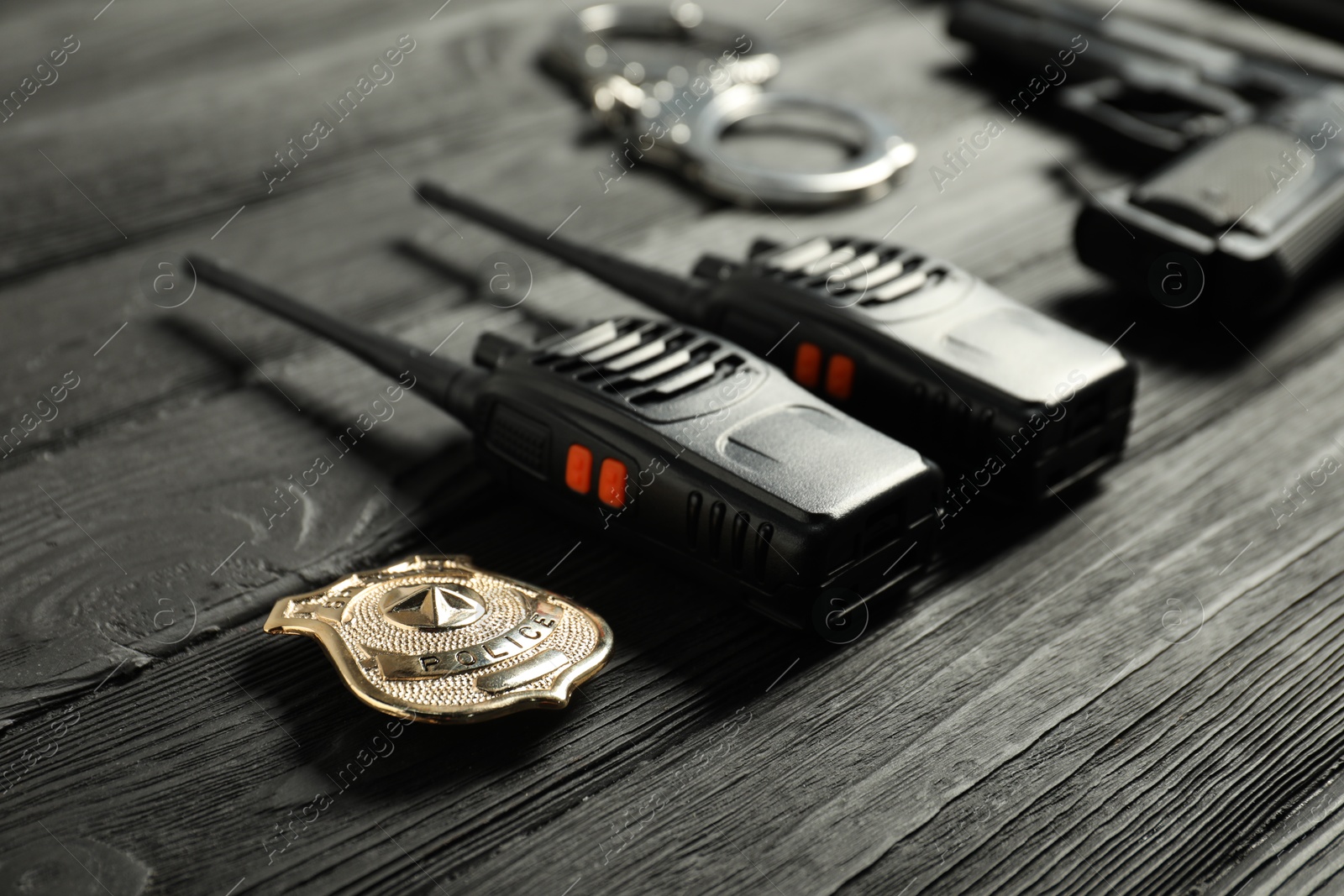 Walkie talkies, badge, gun and handcuffs on black wooden table, closeup. Police equipment Photo of Walkie talkies, badge, gun and handcuffs on black wooden table, closeup. Police equipment