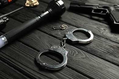 Photo of Different police equipment on black wooden table, closeup
