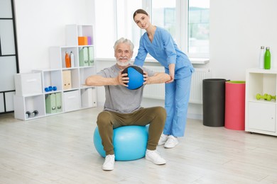 Photo of Doctor and patient exercising with medicine ball in clinic