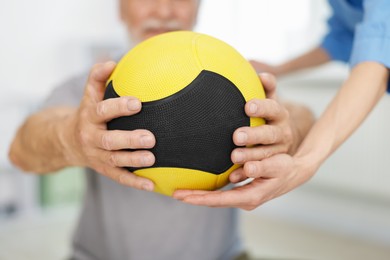 Photo of Doctor and patient exercising with medicine ball in clinic, closeup