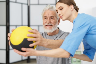 Photo of Doctor and patient exercising with medicine ball in clinic
