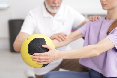 Photo of Doctor and patient exercising with medicine ball in clinic, closeup