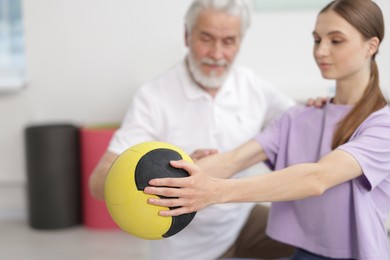 Photo of Doctor and patient exercising with medicine ball in clinic, selective focus