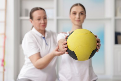 Photo of Doctor and patient exercising with medicine ball in clinic, selective focus