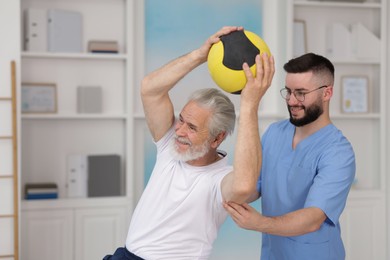 Photo of Doctor and patient exercising with medicine ball in clinic