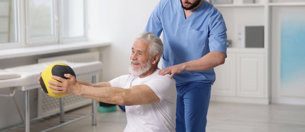 Photo of Doctor and patient exercising with medicine ball in clinic