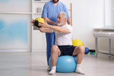Photo of Doctor and patient exercising with medicine ball in clinic, space for text