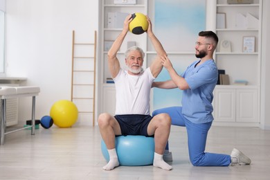 Photo of Doctor and patient exercising with medicine ball in clinic