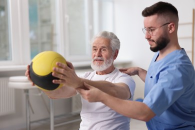 Photo of Doctor and patient exercising with medicine ball in clinic