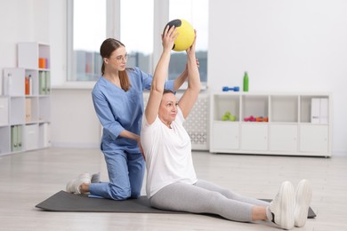 Photo of Doctor and patient exercising with medicine ball in clinic