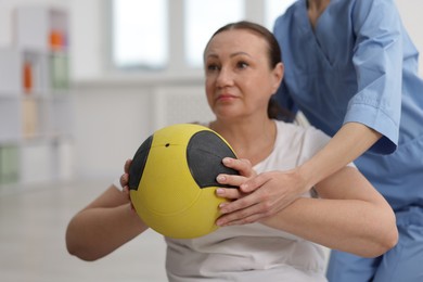 Photo of Doctor and patient exercising with medicine ball in clinic, selective focus