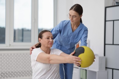 Photo of Doctor and patient exercising with medicine ball in clinic