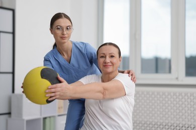 Photo of Doctor and patient exercising with medicine ball in clinic