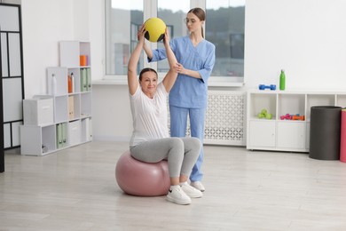 Photo of Doctor and patient exercising with medicine ball in clinic