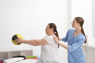 Photo of Doctor and patient exercising with medicine ball in clinic