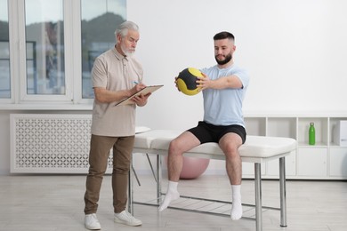Photo of Doctor and patient exercising with medicine ball in clinic