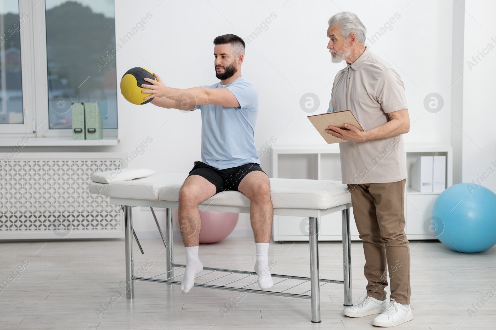 Doctor and patient exercising with medicine ball in clinic Photo of Doctor and patient exercising with medicine ball in clinic