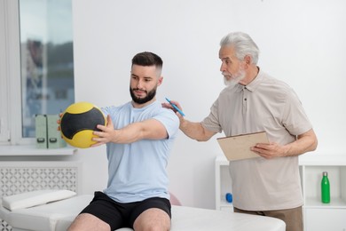 Photo of Doctor and patient exercising with medicine ball in clinic
