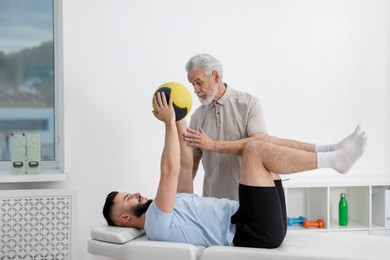 Photo of Doctor and patient exercising with medicine ball in clinic