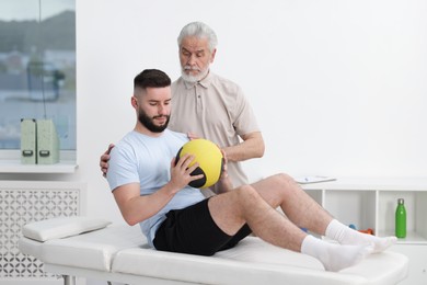 Photo of Doctor and patient exercising with medicine ball in clinic