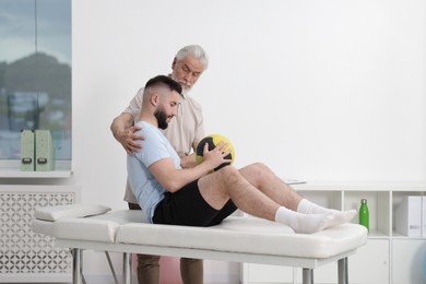 Photo of Doctor and patient exercising with medicine ball in clinic