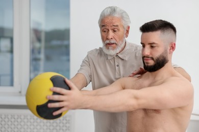 Photo of Doctor and patient exercising with medicine ball in clinic