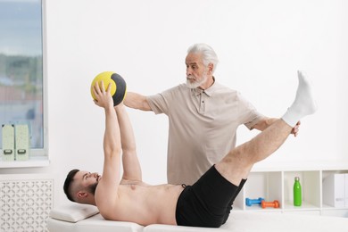 Photo of Doctor and patient exercising with medicine ball in clinic