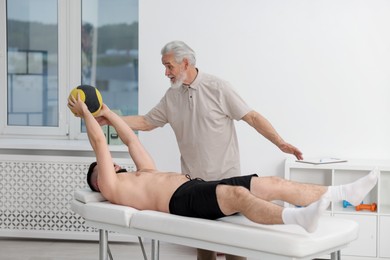 Photo of Doctor and patient exercising with medicine ball in clinic