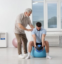 Photo of Doctor and patient exercising with medicine ball in clinic