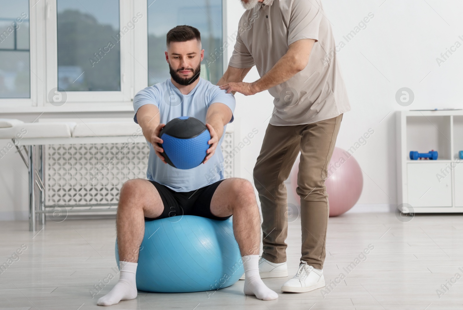Doctor and patient exercising with medicine ball in clinic, space for text Photo of Doctor and patient exercising with medicine ball in clinic, space for text