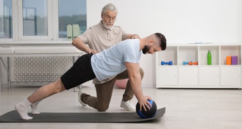 Photo of Doctor and patient exercising with medicine ball in clinic