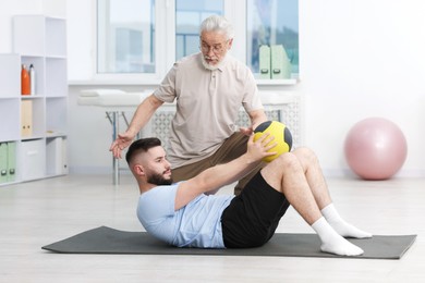 Photo of Doctor and patient exercising with medicine ball in clinic