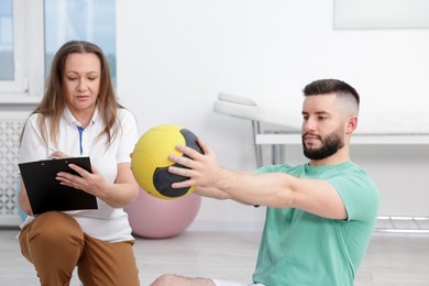 Photo of Doctor and patient exercising with medicine ball in clinic