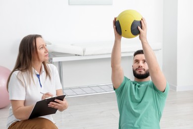 Photo of Doctor and patient exercising with medicine ball in clinic