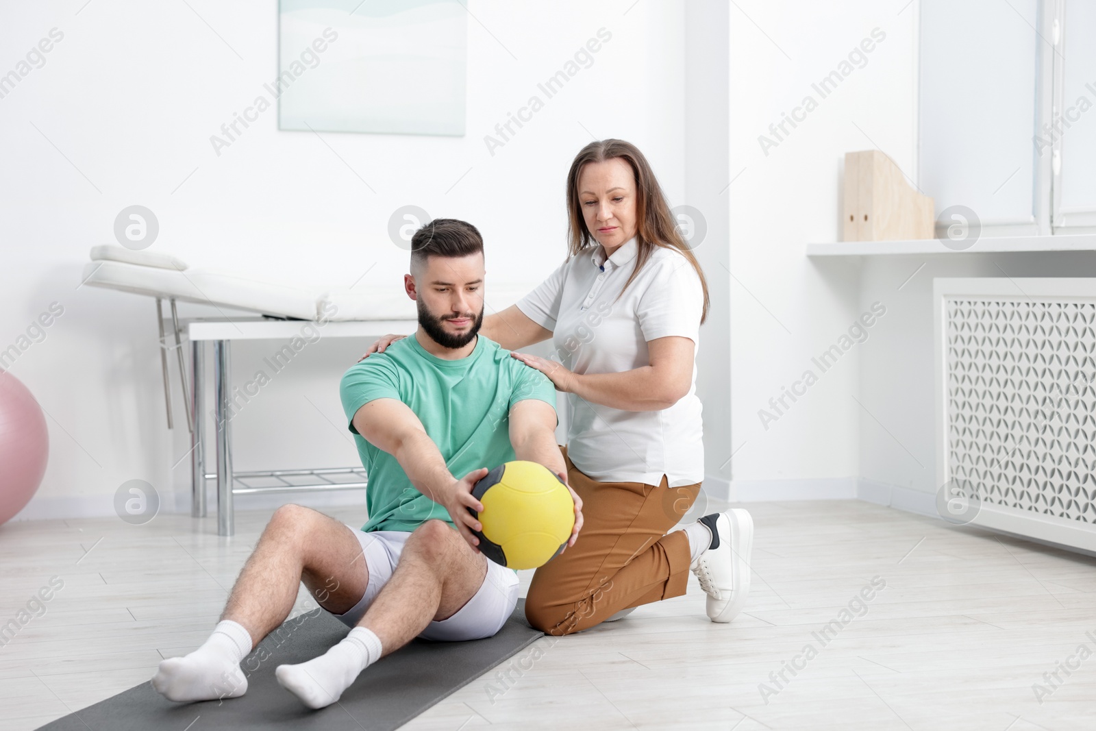 Doctor and patient exercising with medicine ball in clinic Photo of Doctor and patient exercising with medicine ball in clinic